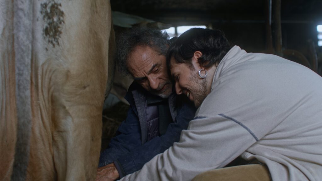 Xuan and Luca share an intimate moment while milking a cow in a rural Asturian barn, in the short film IUS of Time (2025).