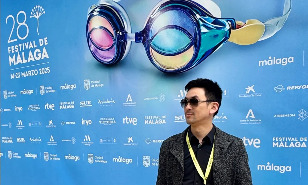 Director Xu Xiaoxi posing next to the official banner of the Málaga Film Festival, where the short film “IUS of Time” participated in MAFIZ, Spain, 2025.