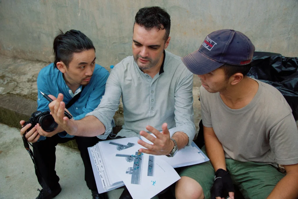 Roberto F. Canuto and Xu Xiaoxi reviewing storyboard with cinematographer Guo Yong on set
