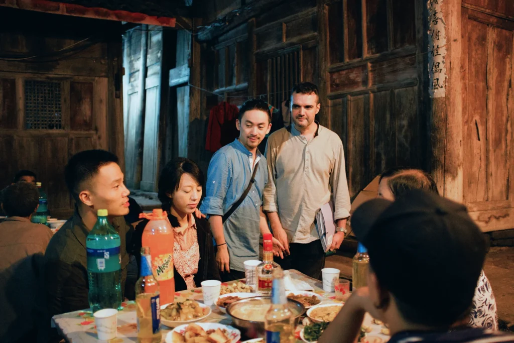 Directors Roberto F. Canuto and Xu Xiaoxi with cast during rural dinner scene filming Sunken Plum in China
