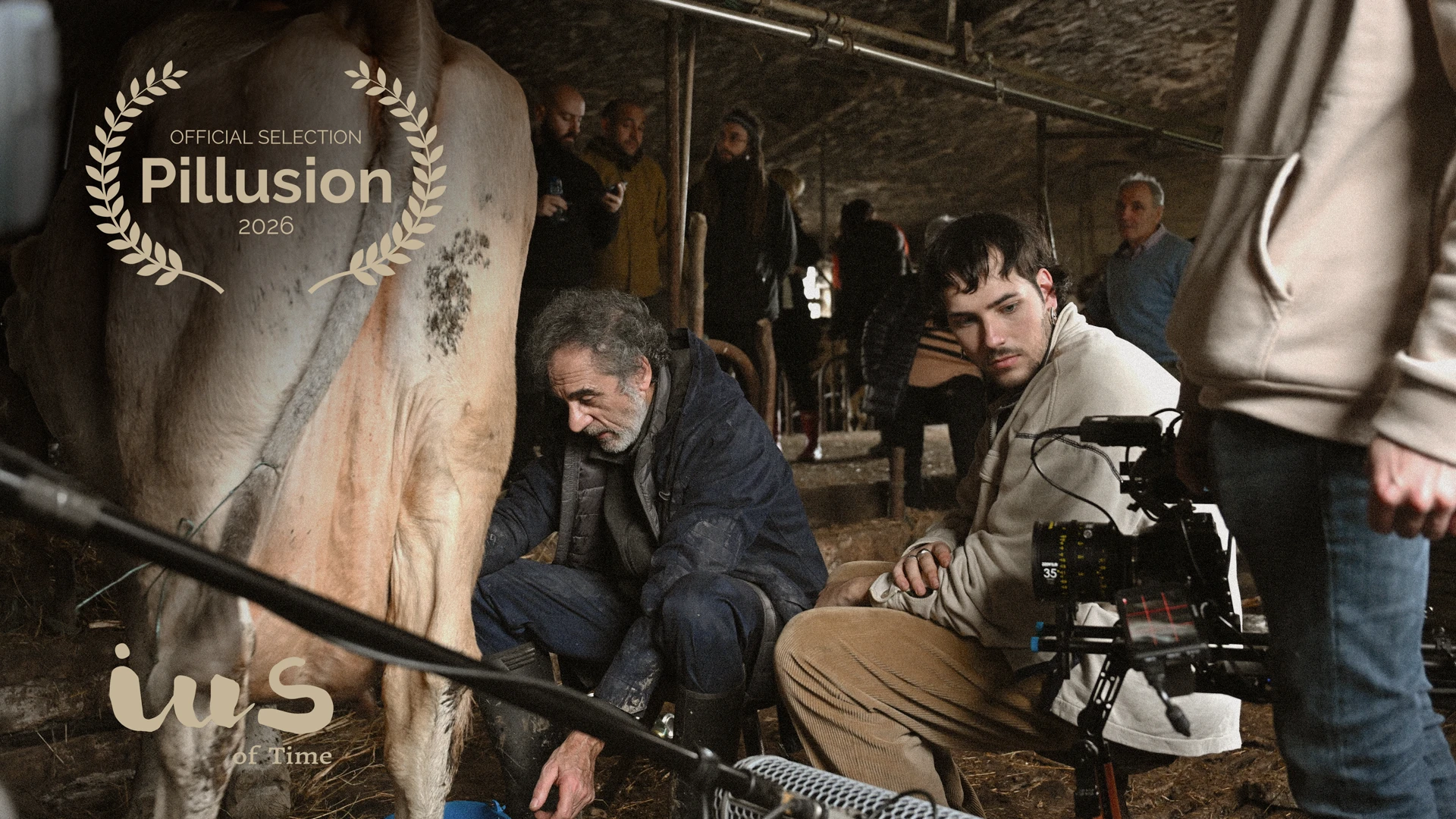 Behind the scenes of IUS of Time in Asturias: actors Pelayo Carrizo (Luca) and Manuel Pizarro (Xuan) with the film crew, camera and boom mic beside a cow, official selection at the 5th Pillusion Film Festival 2026